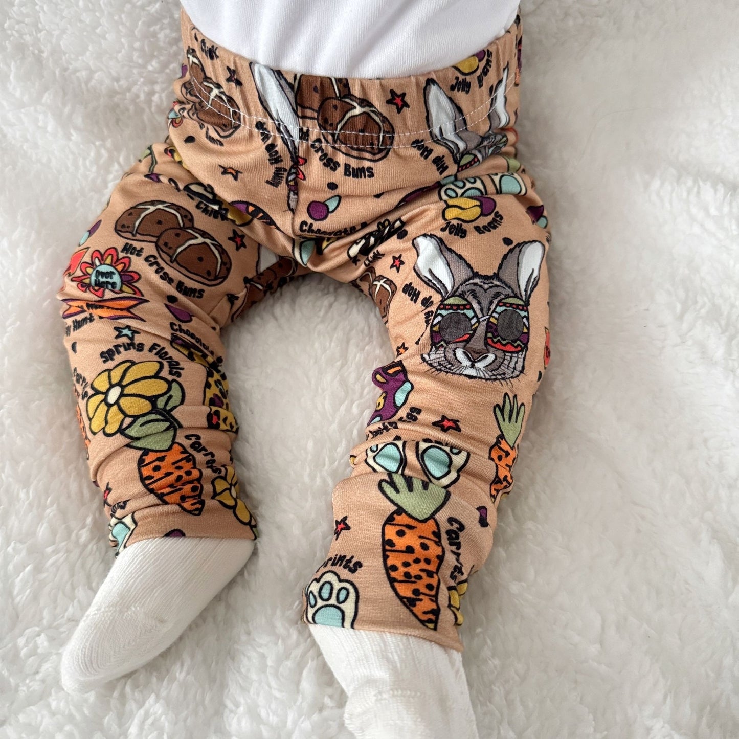 A pair of beight leggings with easter images on them being worn by a baby.