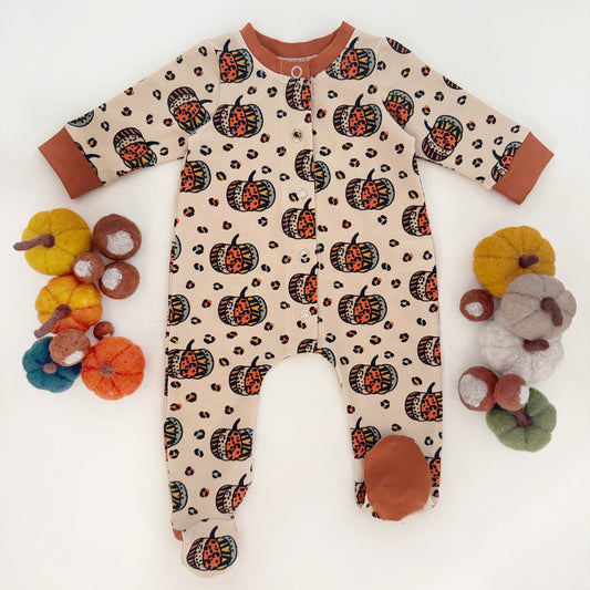 Baby onesie with pumpkin pattern surrounded by colorful pumpkins on a white background